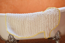Load image into Gallery viewer, white crochet duck rug with yellow outline hanging on a bathtub