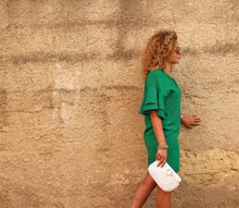 Load image into Gallery viewer, girl with green dress walking by a wall holding a white bag

