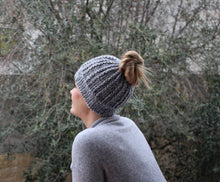 Load image into Gallery viewer, girl looking out in nature wearing a gray messy bun beanie
